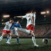 Białoczerwony piłkarz na boisku uderza z woleja niską piłkę